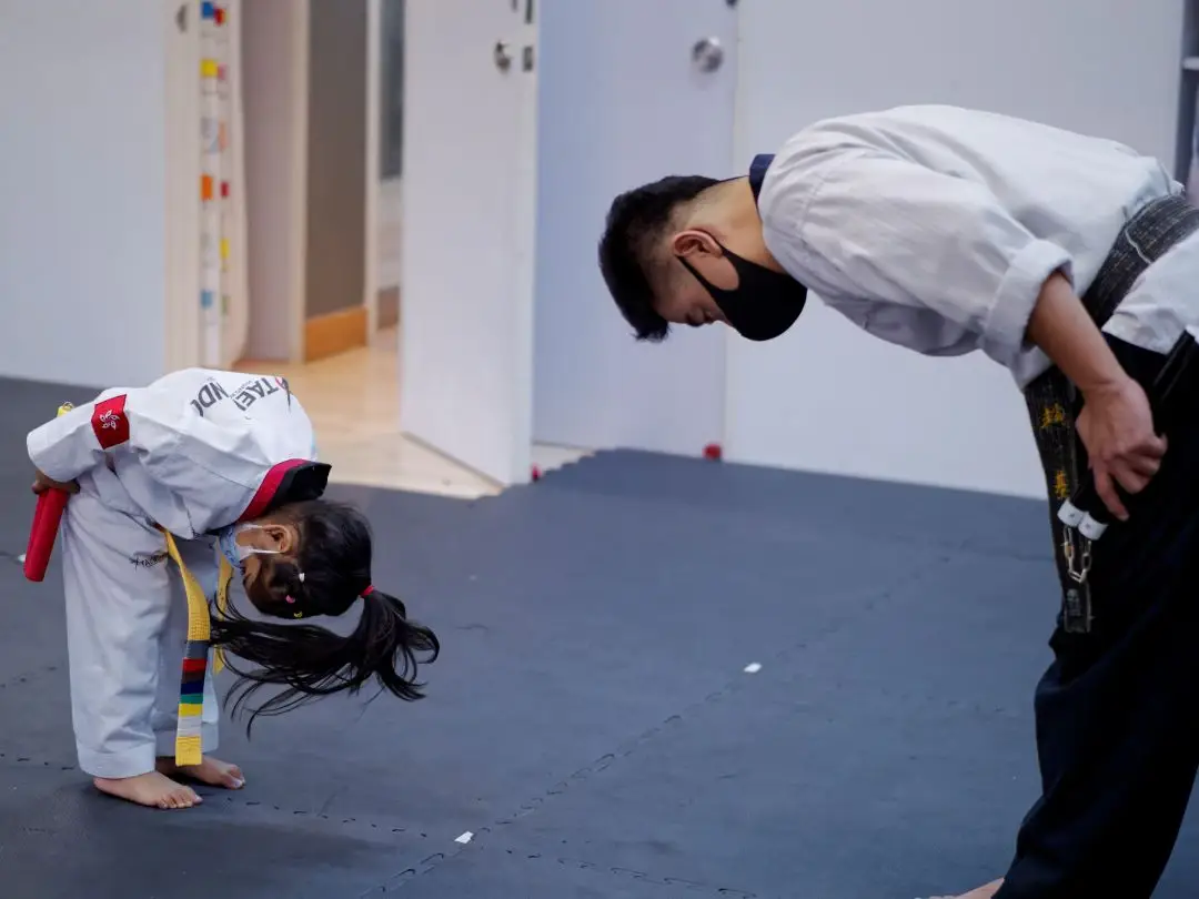 Master and child student bowing to each other at TNT Taekwondo Wan Chai, demonstrating respect and discipline.